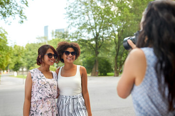 female friendship, technology and people - woman with camera photographing her friends in summer park