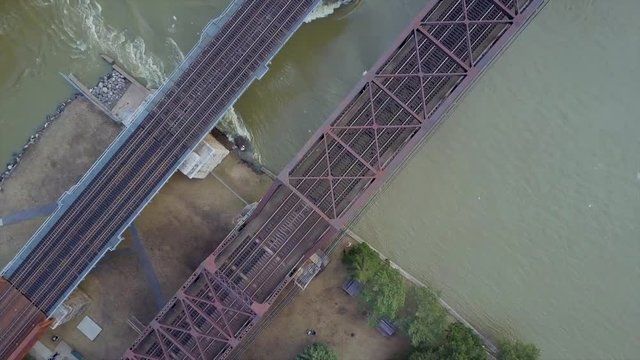 Cinematic drone / aerial footage moving sideways showing the water currents of Saint Lawrence River under a train rail in Montreal, Quebec, Canada during pre-spring season.