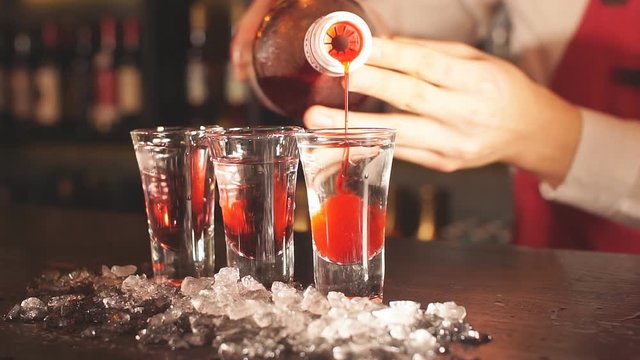Red cocktail shots in glass isolated on blurred restaurant background.