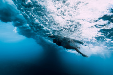Fototapeta premium Surfer woman dive underwater. Surfgirl dive under big wave