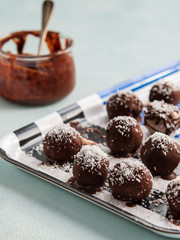 Homemade Healthy Paleo Raw Chocolate Truffles or balls with Nuts, Dates and coconut on light Background.
