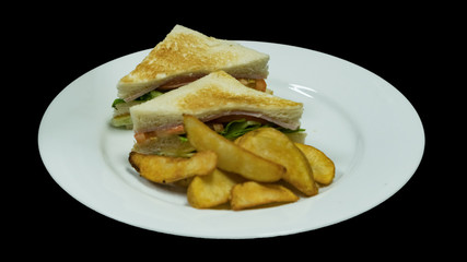 Tuna sandwich, potato chips in a white dish on a black background