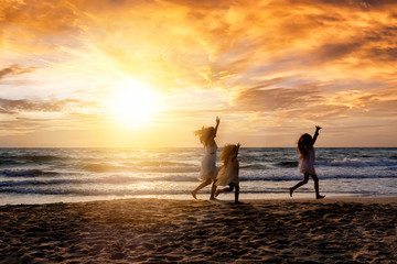 Mutter und ihre Kinder haben Spa&szlig; am Strand bei Sonnenuntergang w&auml;hrend ihres Sommer Urlaubes