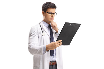 Young male doctor looking at a paper on a clipboard and thinking