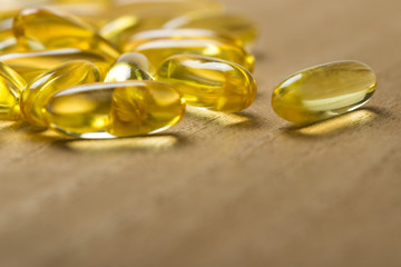 Pile of fish oil omega 3 gel capsules on wooden board