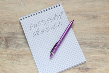 notepad  with the inscription Successful Desision, with  pen on the table