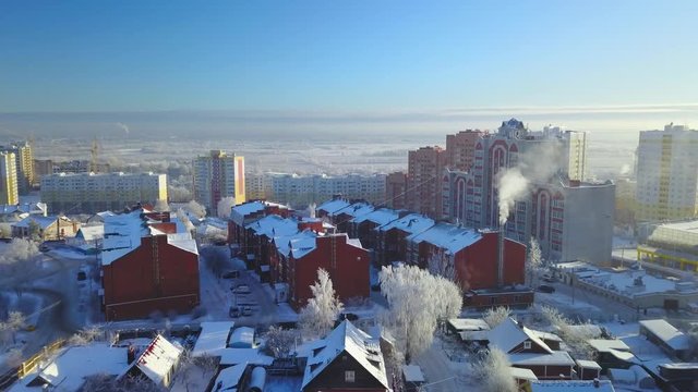 Aerial view Flying over snow-covered town at winter sunny dat