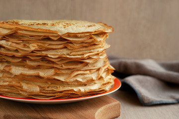 A stack of thin pancakes close-up. Pancake week. A lot of thin pancakes on wooden background. A stack of pancakes in the kitchen.