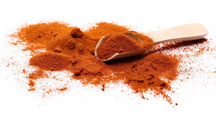 Red paprika powder pile with wooden spoon isolated on white background