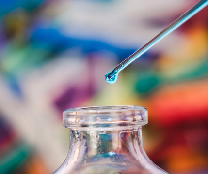Primer plano de una pipeta dejando caer un l&iacute;quido azul