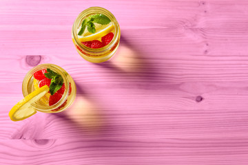 flat lay of lemonade with berries on pink table