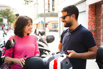 Young couple putting on helmet to ride a motorcycle