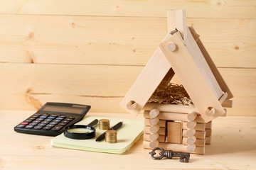 Model of log house and an iron  key on the wooden background. Business concept.