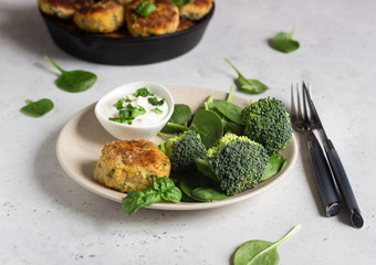 Delicious fried meat cutlets. Chicken or turkey cutlets with carrot and spinach served with broccoli, spinach and sour cream sauce. Light grey concrete background.