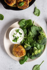 Delicious fried meat cutlets. Chicken or turkey cutlets with carrot and spinach served with broccoli, spinach and sour cream sauce. Light grey concrete background.