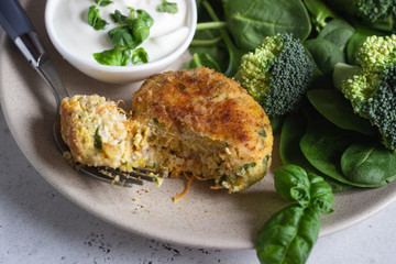 Delicious fried meat cutlets. Chicken or turkey cutlets with carrot and spinach served with broccoli, spinach and sour cream sauce. Light grey concrete background.