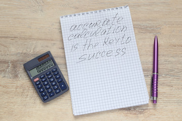 notepad  with the inscription Accurate Calculation Iis The Key To Success with a open calculator and pen