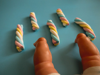 Candies with cloud shape on a sky blue background next to a baby toy