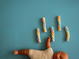 Candies with cloud shape on a sky blue background next to a baby toy