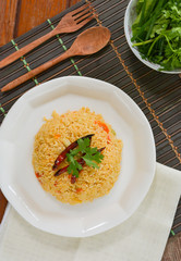Tomato fried with dried chili rice on white dish and wooden table for served in cafe and restaurant.  