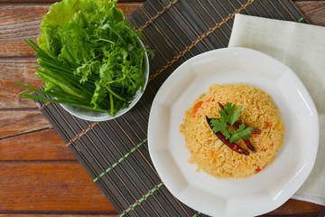 Tomato fried with dried chili rice on white dish and wooden table for served in cafe and restaurant.  