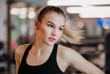 A portrait of young girl or woman standing in a gym.