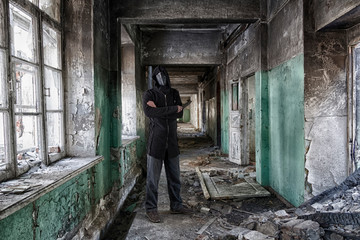 Danger maniac with knife in hand, in leather mask of lague doctor and hood, inside old abandoned house