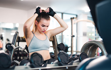 A portrait of young girl or woman doing exercise in a gym.