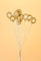 Small bagels on ropes fly up on a yellow background. The concept of bagels like balloons.