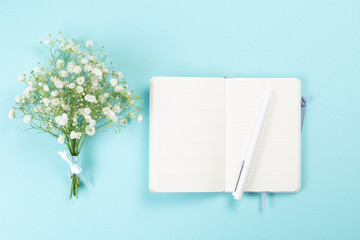 Good morning concept - coffee, flowers, notebook, blue background top view