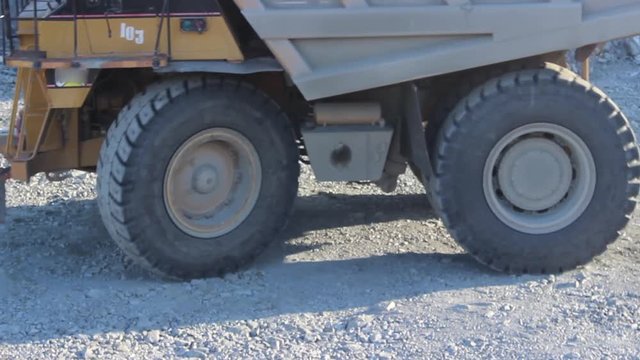 Huge career dump truck working in a career.  An excavator in a quarry loads a dump truck with rock, soil, stones.