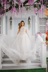 Fototapeta na wymiar Elegant girl in a white dress posing in a flowering room