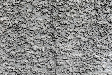 Grey concrete wall with rough surface and big crack