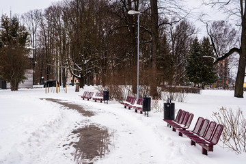 Red metal park benches covered in snow isolated 