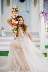 Fototapeta premium A charming girl in a white dress sitting on the swing