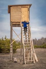 Man on a wooden hunting tower for archery of wild animals