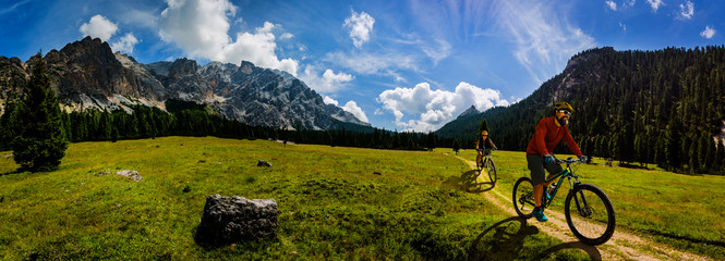 Cycling woman and man riding on bikes in Dolomites mountains andscape. Couple cycling MTB enduro trail track. Outdoor sport activity. © Gorilla