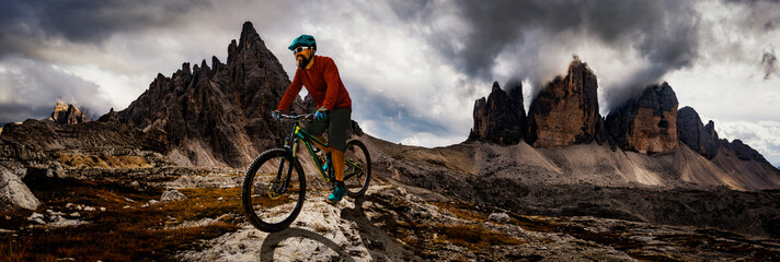 Tourist cycling in Cortina d'Ampezzo, stunning rocky mountains on the background. Man riding MTB...