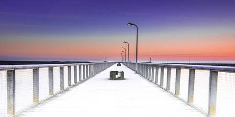 Fototapeta premium Wooden pier and colourful sunset sky in Amble, Northumberland