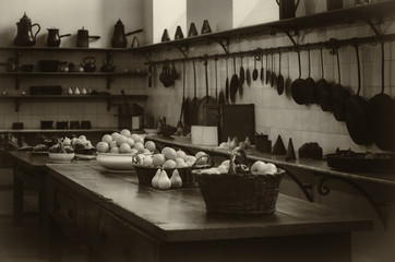 vintage looking image of an antique XIX century old kitchen with tools, pans, pots and food...