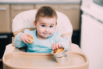the little girl in the highchair in the hands Krapina, like muffins and croissants trend 2019