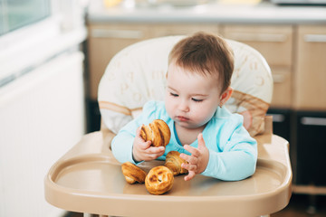 the little girl in the highchair in the hands Krapina, like muffins and croissants trend 2019