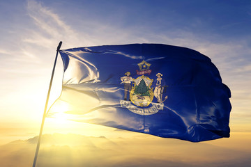 Maine state of United States flag waving on the top sunrise mist fog