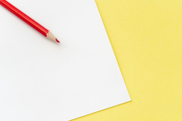 Close-up of red pencil on the white and yellow background. 