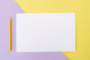 Yellow pencil and white piece of paper on yellow and purple background. Art, scool or office shoot