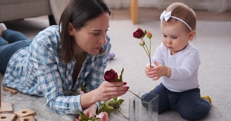 Mother and cute baby daughter arranging rose flowers in vase