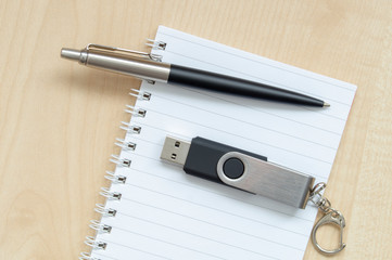 notebook pencil USB flash drive on wooden background