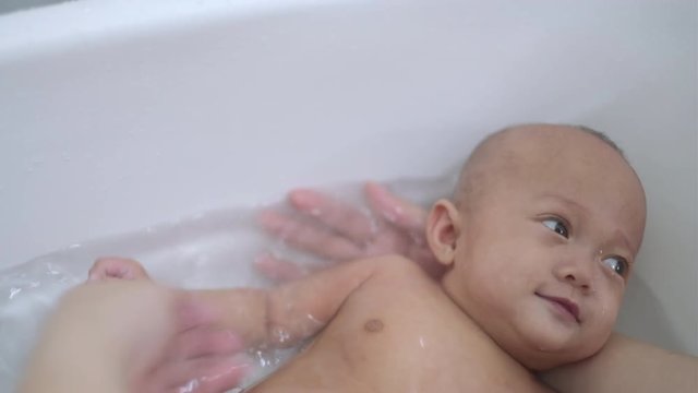 Cute smiling Asian 2 -3 months old newborn baby girl child taking a bath, Little daughter having fun in bath time in bathroom with mother, Infant washing and bathing, Hygiene & care for young children