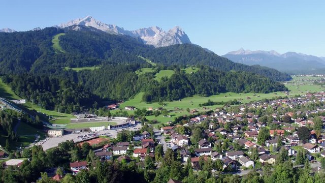 Drone flies over Garmisch-Partenkirchen and opens up a beautiful view of the olympia chanze and zugspitze in the background