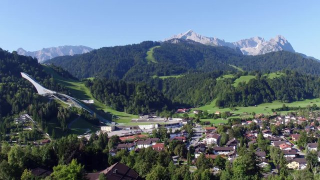 Drone flies over Garmisch-Partenkirchen and opens up a beautiful view of the olympia chanze and zugspitze in the background
